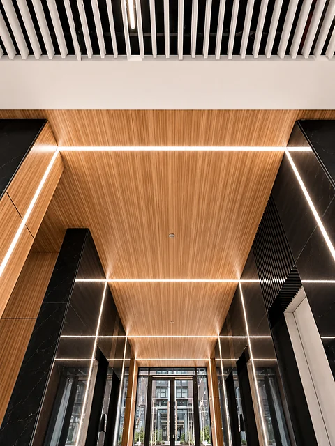 Symmetrical corridor clad in timber panels with linear ceiling lights