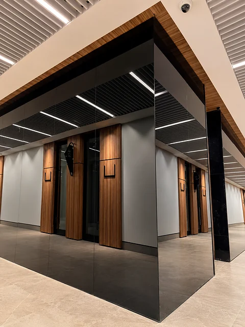 Dark lobby with timber cladding, glass partitions and stone floor