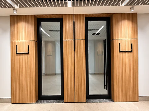 Glazed office doors framed by timber panelling