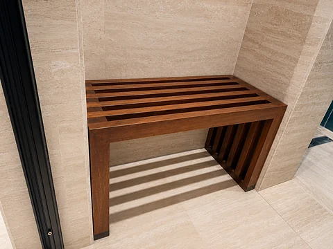 Slatted timber bench against a stone-clad wall
