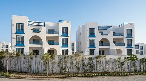 Row of finished white apartment blocks behind a landscaped wall